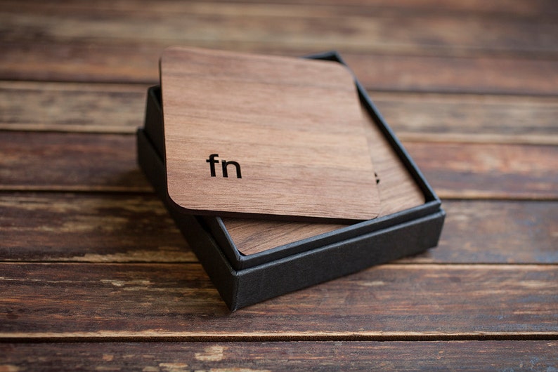May include: A set of wooden coasters in a black box. The top coaster has the letters "fn" engraved on it.