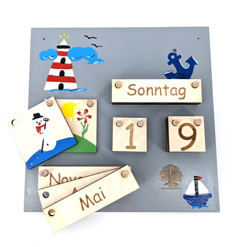 May include: A wooden calendar with interchangeable cards for days of the week, dates, months, and weather. The calendar features a lighthouse, a snowman, a flower, an anchor, and a sailboat.