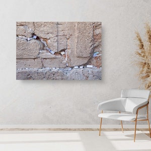 Puede incluir: Primer plano de un gran muro de piedra erosionado con una grieta que lo atraviesa. El muro está cubierto de pequeños trozos de papel, probablemente oraciones o deseos dejados por los visitantes.