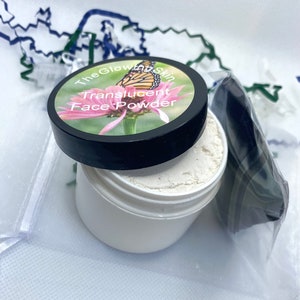 Może przedstawiać: Biały plastikowy słoik z czarną pokrywką. Pokrywka ma naklejkę z różowym kwiatem, motylem i tekstem "The Glowing Skin Translucent Face Powder".