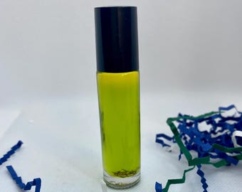 May include: A small glass bottle with a black cap and a bright green liquid inside. The bottle is sitting on a white surface with blue and green paper shreds.