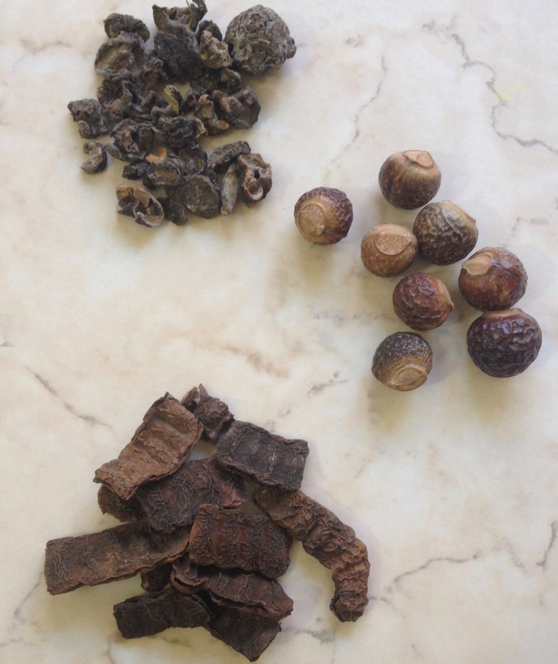 May include: A collection of dried herbs and nuts, including brown and black dried leaves, and brown round nuts.