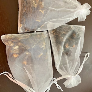May include: Three white mesh bags filled with dried black mushrooms. The bags have white drawstrings and are tied at the top.