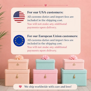 May include: Six rectangular storage boxes arranged in two stacks of three. The boxes are pastel pink and light blue, each featuring a small gold-toned latch and a decorative pink flower on the lid. The boxes sit on a light-coloured wooden surface.