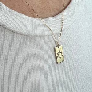 May include: A gold chain necklace with a rectangular pendant featuring a Star of David design.