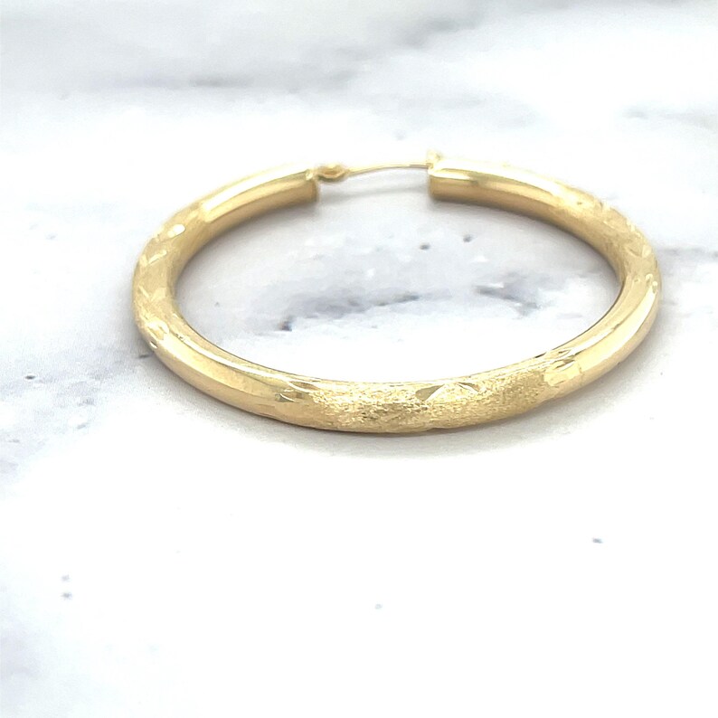 14K Yellow Gold Diamond Cut Textured Design Hoop Earring photographed on its own
