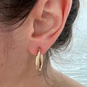 Gold hoop earring worn on the ear
