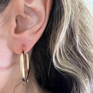 Gold hoop earring worn on the ear