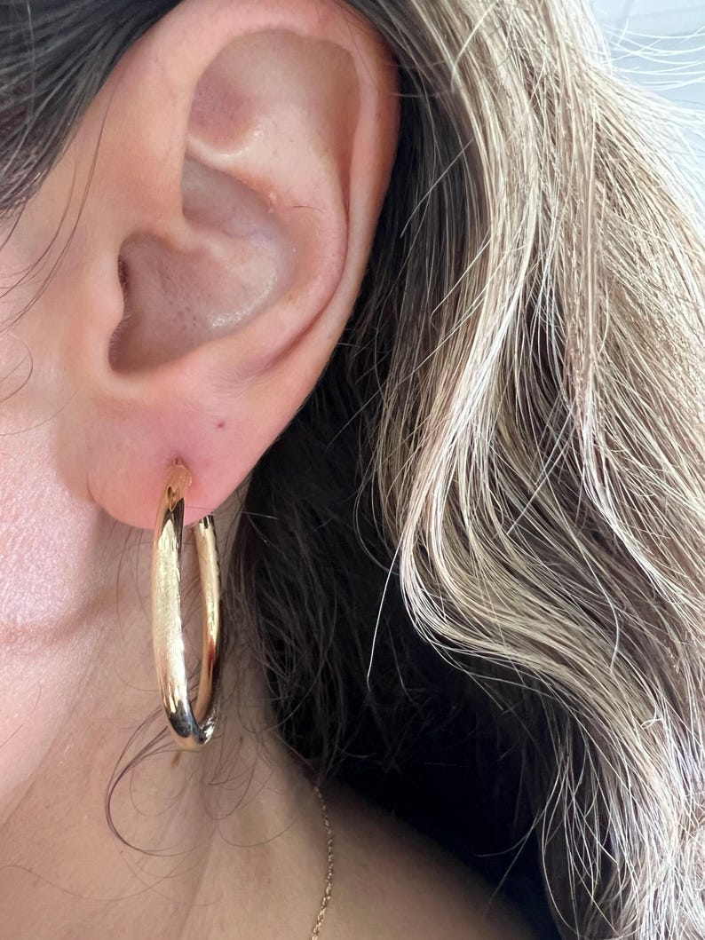 Gold hoop earring worn on the ear