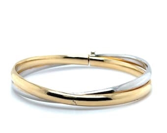 May include: A gold and silver bangle bracelet. The bracelet features a gold band that crosses over a silver band. The bracelet has a clasp closure. The jewelry is displayed on a white background.