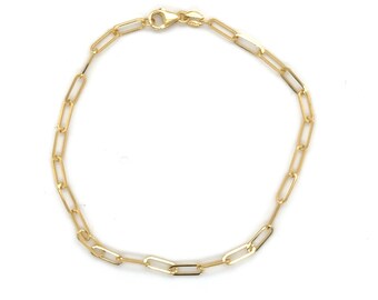 May include: A gold chain bracelet featuring elongated, rectangular paperclip-style links. The bracelet is connected by a small, polished gold lobster claw clasp at the top, forming a continuous circular loop against a plain white background.