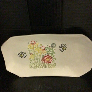 May include: White ceramic serving tray with a floral design featuring yellow and red flowers and green leaves. Two yellow bees are on the tray.