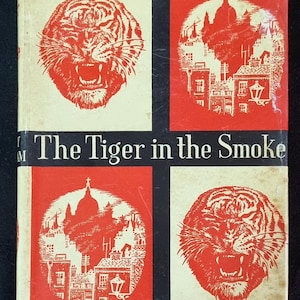 Puede incluir: Portada de libro vintage de "The Tiger in the Smoke" de Margery Allingham. La portada presenta una ilustración de un tigre rojo y una ilustración roja y blanca de una ciudad. El título y el nombre del autor son en blanco.