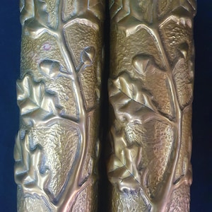 May include: Two gold-colored metal candle holders with a textured design of leaves and vines.