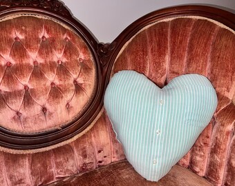 May include: A vintage, ornately carved, red velvet sofa with a heart-shaped, striped, light blue pillow.