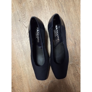 May include: A pair of black Rangoni Firenze heels. The shoes have a square toe and a low heel. The brand name is printed in white on the insole. The shoes are made in Italy.