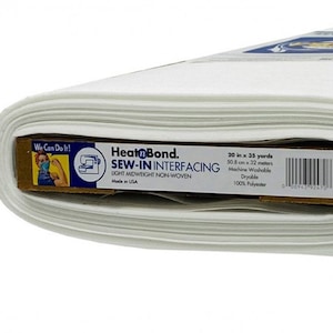 May include: A roll of white HeatnBond Sew-In Interfacing fabric. The label indicates the roll is 20 inches by 35 yards. The fabric is lightweight, non-woven, machine washable, and made of 100% polyester. The roll is partially unrolled.