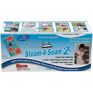 May include: A blue and white box with the text "Steam-A-Seam 2" and a picture of an iron. The box is for a double stick fusible web for appliqués. The text "New Grid Aids in Tracing! Easy to See Through and Write On!" is on the box.