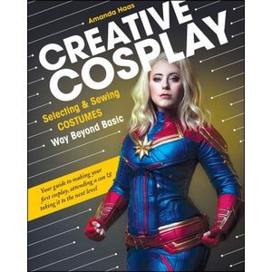 May include: Book cover with the title "Creative Cosplay: Selecting & Sewing Costumes Way Beyond Basic". The cover features a woman dressed as Captain Marvel, a superhero from the Marvel Cinematic Universe.