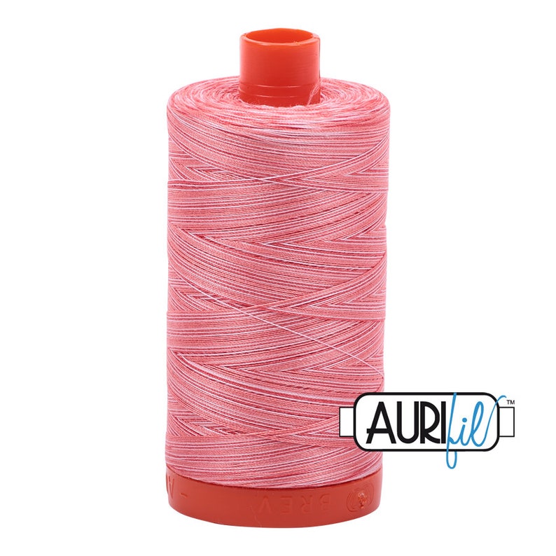 May include: A spool of Aurifil thread in a vibrant pink color, with white threads interwoven throughout. The spool has a bright orange top and base. The Aurifil logo is visible on the side. This thread is ideal for sewing and quilting projects.