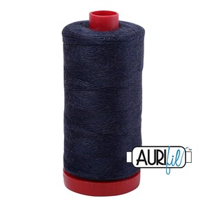May include: A spool of navy blue thread with a red base and top. The thread is tightly wound, and the spool has the Aurifil logo on the side. This thread is likely used for sewing or quilting projects.