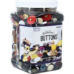 May include: A clear plastic jar filled with assorted buttons in various colors and styles. The jar has a white lid and a label that reads "Not your Grandma's BUTTONS". The buttons include red, black, yellow, and white.