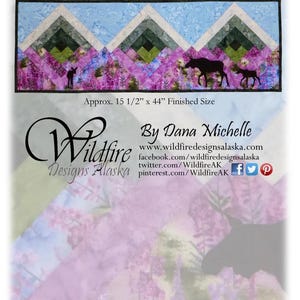 May include: A fabric wall hanging with the text "Wait Up!" and a landscape design. The design includes geometric shapes, a moose and calf silhouette, and purple flowers. Finished size is approximately 15.5 inches by 44 inches.