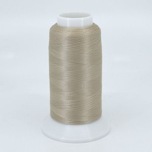 May include: A spool of beige thread wound on a white plastic bobbin.