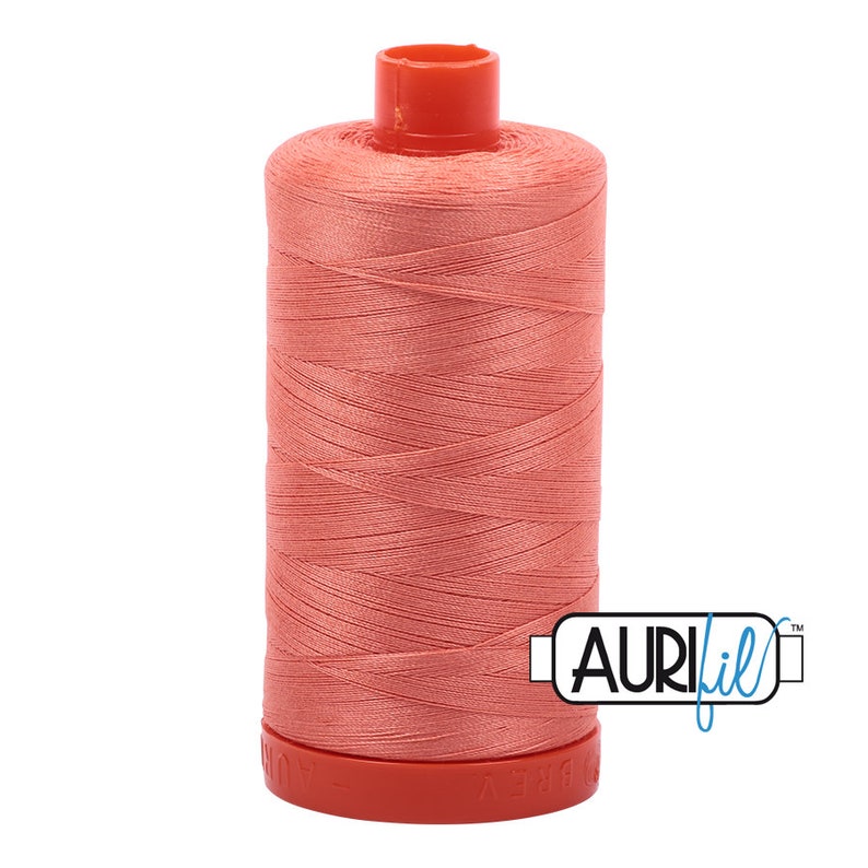 May include: A spool of coral-colored thread with a red top and base. The thread is tightly wound around the spool. The brand name "AURIfil" is printed on the side.