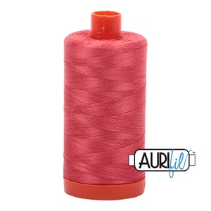 May include: A spool of coral-colored Aurifil thread. The thread is tightly wound around a cylindrical core, with a bright orange top and base. The Aurifil logo is visible on the side. Ideal for sewing and quilting projects.