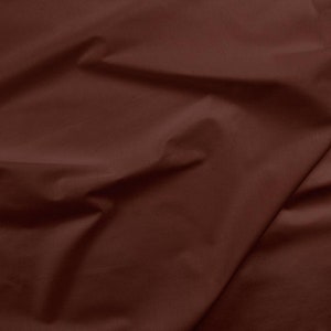 May include: A close-up of a smooth, dark brown fabric with a soft, wrinkled texture.
