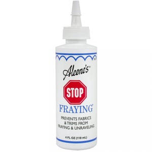 May include: A white bottle of Aleene's Stop Fraying fabric sealant. The bottle has a red stop sign with the word "STOP" in white letters. The bottle label says "PREVENTS FABRICS & TRIMS FROM FRAYING & UNRAVELING" and "4 FL OZ (118 mL)".