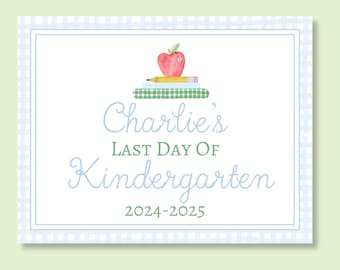 May include: A watercolor-style sign with a light blue gingham border. The sign reads "Charlie's Last Day of Kindergarten 2024-2025" in blue script. An apple and pencil rest atop a stack of books.