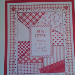 May include: A counted cross stitch pattern for a baby girl's birth announcement. The pattern features a patchwork quilt design with a pink and white color scheme. The text reads "Amy Reese Arrived 8-22-05 Weight 7lb 4oz."