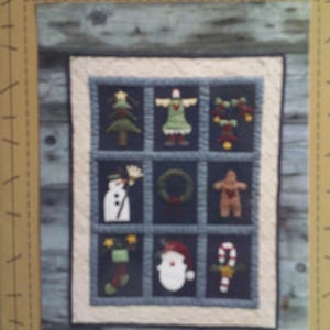May include: A Christmas-themed quilt with nine squares, each featuring a different holiday icon. The icons include a Christmas tree, a figure in a green dress, ornaments, a snowman, a wreath, a gingerbread person, a stocking, Santa Claus, and a candy cane.