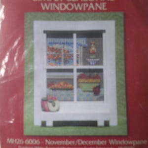 Puede incluir: Un kit de punto de cruz Mill Hill Simply Seasonal Windowpane con fondo rojo. La imagen muestra un marco de ventana blanco con cuatro paneles que exhiben elementos estacionales como manzanas, un cuenco y un patrón de cortina a cuadros azules.