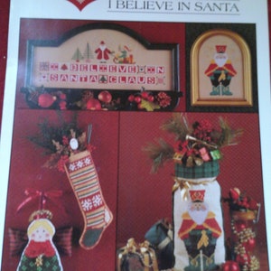 Puede incluir: Patrón de punto de cruz para una media de Navidad con un diseño de Papá Noel. El patrón incluye una media con diseño de cuadros, una media con diseño de copo de nieve y una media con diseño de muñeco de nieve. El patrón también incluye un pequeño adorno de ángel. El patrón se titula "Creo en Santa Claus" y está diseñado por Renée Nanneman.