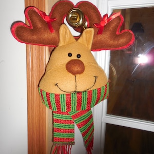 May include: A brown reindeer head with red and white antlers and a green and red striped scarf with gold glitter.