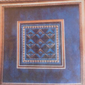 Op de afbeelding: Een ingelijst kunstwerk met een blauwe achtergrond en een geometrisch patroon in tinten blauw, zwart en wit.