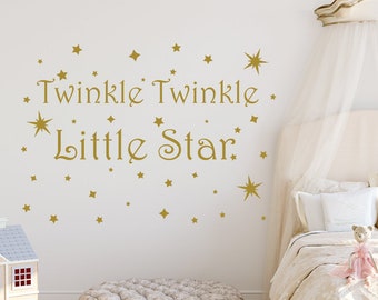 May include: Gold vinyl wall decal featuring the words "Twinkle Twinkle Little Star" and a scattering of stars. The decal is on a white wall in a bedroom with a bed and a footstool.