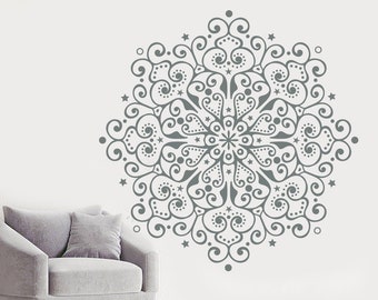 May include: A grey mandala wall decal with intricate swirling patterns and small stars. The decal is applied to a white wall behind a grey armchair.