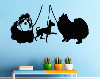 May include: Silhouette wall decal of three dogs on leads. The dogs are a Shih Tzu, a Chihuahua, and a Pomeranian. The decal is black and is set against a light blue wall.