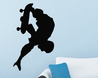 May include: Black silhouette of a person performing a skateboard trick on a wall. The person is upside down with their legs in the air and their arms outstretched. The skateboard is beneath their feet.