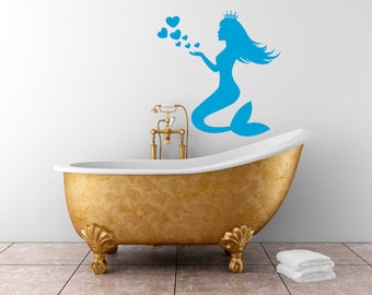 May include: A blue mermaid silhouette with a crown blowing hearts on a white wall above a gold bathtub.