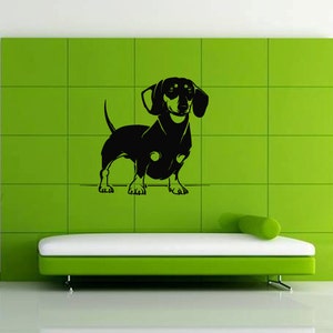 May include: Black silhouette of a dachshund dog standing on a green tiled wall. The dog is facing forward with its head tilted slightly to the side.
