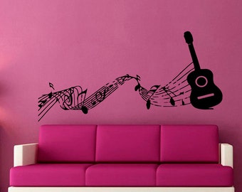 May include: Black and white wall decal featuring a guitar with musical notes flowing from it. The decal is on a pink wall above a pink sofa.