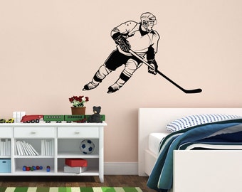 May include: Black and white silhouette of a hockey player skating and holding a hockey stick. The image is on a white wall in a room with a white bed and a white dresser.
