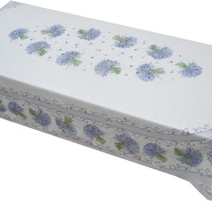 May include: White tablecloth with a blue and green floral pattern. The pattern features bunches of small blue flowers with green stems and leaves. The tablecloth has a decorative border with a scrolling design.