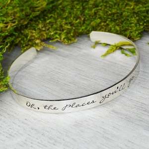 May include: Silver bangle bracelet with the inscription "Oh, the places you'll go" engraved on the front.