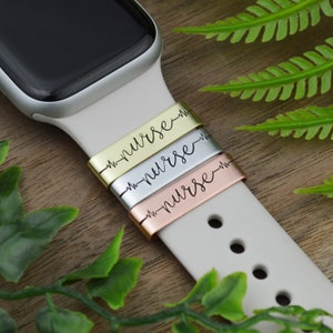 Könnte beinhalten: Drei Apple Watch Armbänder mit einem Herzschlag und dem Wort "nurse" eingraviert. Die Armbänder sind in Gold, Silber und Roségold.